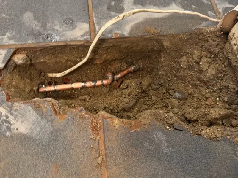 The copper pipe exposed under the kitchen floor at the leak