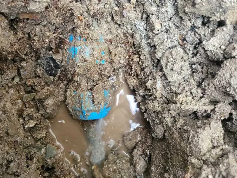The failed lead supply pipe exposed beneath the outside wall